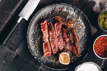 Succulent Farmhouse Rustic Rump Steak with thyme garnish shot against a dark background with wood burner. The perfect image for your bistro or restaurant menu cover art. Copy space.