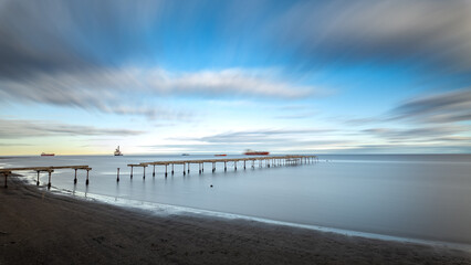 Serene seascape with long pier under a dynamic sky