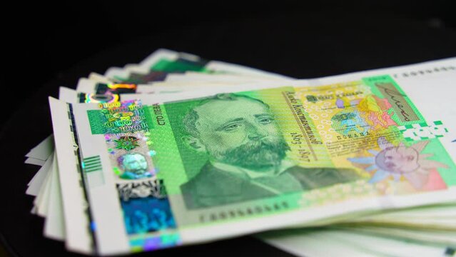 Thick stack of Bulgarian 100 leva bills rotates in front of the camera with shallow depth of field