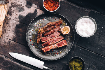 Succulent Farmhouse Rustic Rump Steak with thyme garnish shot against a dark background with wood...
