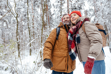 Fototapeta premium Man and woman in warm clothes spending time in a winter forest