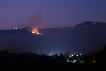 Forest fires on the mountain at night, you can see fires in villages on the mountain. Compared to the light of a forest fire, it looks even more frightening. Forest fire in Chiang Mai, Thailand
