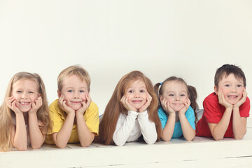 Five happy children (three girls and two boys) pose in white studio