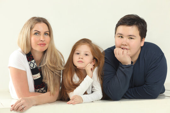 Family (mother, daughter and son) are on white floor in white studio