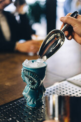 Expert barman is making cocktail at night club.