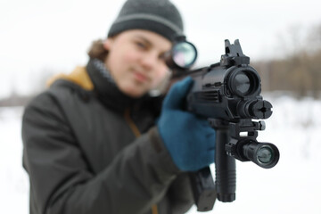 Teenager with gun takes aim during lasertag game outdoor at winter, focus on muzzle