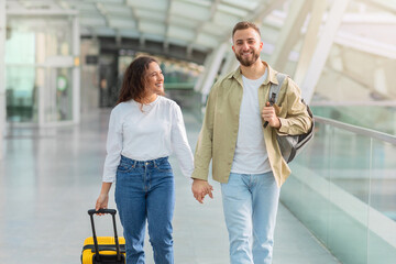 Portrait of romantic young couple walking together in airport terminal,