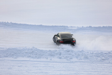 Black car races among snow track at Pirogovskoe reservoir