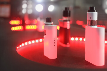 Electronic Cigarettes are on table with red illumination, shallow dof