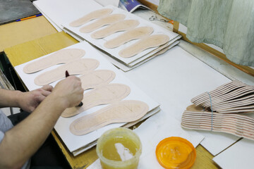 Male hands makes marking on details for shoes at modern shoes factory