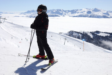 Fototapeta na wymiar Boy in ski goggles stands on mountain with cableway in ski resort at winter day