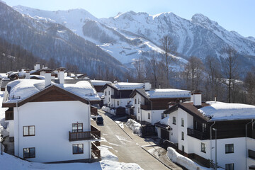 Beautiful cottages with balconies in village among mountains at ski resort at winter day