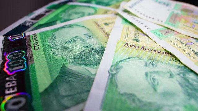 Macro shot of rotating Bulgarian currency: 100 leva bills are spread on the table.