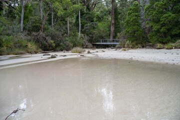 Sandy beach, next to the sea with waves breaking behind, and mountains in the distance