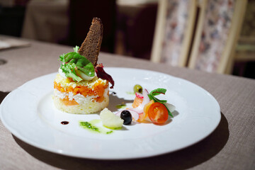 Layered salad served with round shape decorated with bread on plate in restaurant