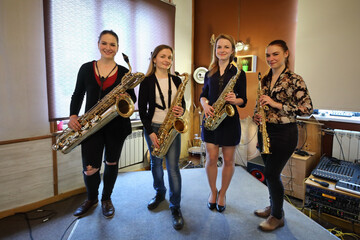Four women poses with wind instruments in sound recording studio