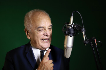 Radio host speaking to his audience. Mature man speaking with a microphone at a radio station....