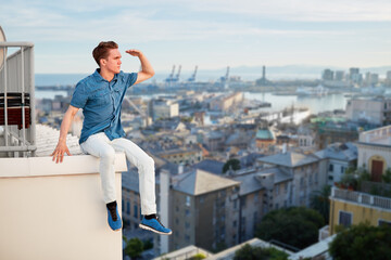 Young man in looks afar, sits on edge of roof in seaport, collage