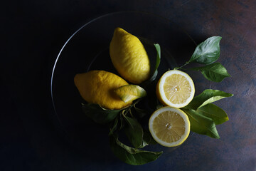 Limoni su un piatto; still life con vista dall’alto, composizione su fondo scuro