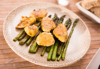Fried chicken breast pieces with asparagus on white plate