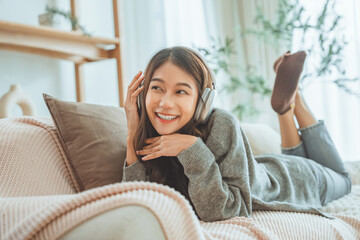 Happy asian woman listening to music from mobile phone while sitting on the the sofa at homes, Smiling girl relaxing with headphones in morning, Time to relax