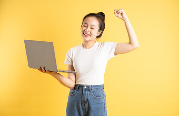 Portrait of Asian woman using computer and  posing on yellow background