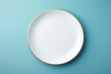 Elegant white plate with gold rim on blue background. Perfect for food and dining concepts