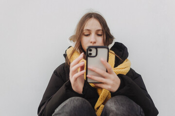 Half length portrait of girl in casual wear holding smartphone for blogging outdoors