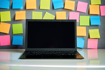 Modern laptop and blank colorful sticky notes on wall background - 762347567