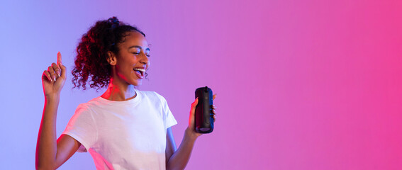 Happy black lady enjoying music with speaker on dual-tone background, panorama, free space