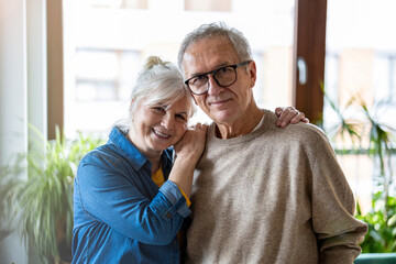 Portrait of happy senior couple embracing each other in living room at home
