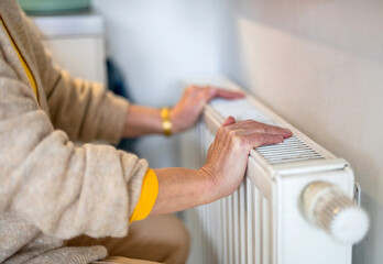 Senior woman checking heating radiator in her apartment
