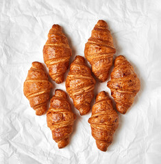 Freshly baked croissants on white baking paper. Top shot, flat lay. Homemade food concept