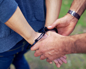 Police officer, hands and closeup to arrest person for crime with safety, legal and security service. People, law enforcement and outdoor for justice, peace or stop danger in society with handcuffs