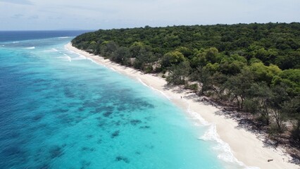 Scenic aerial view of Jaco Island with crystal clear turquoise ocean water, white sandy beach and forest trees on remote uninhabited tropical island