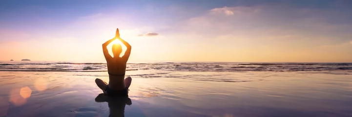 Wandcirkels aluminium Wellbeing and mindfulness through yoga practice. Silhouette of a fit woman yogi in lotus pose on a calm beach at sunset. Harmony, balance, serenity and spirituality in meditation. Healthy lifestyle. © NicoElNino