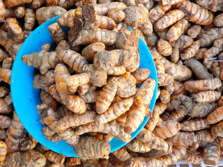 A plate and piles of homegrown turmeric on stall at local fruit and vegetable market in Timor-Leste, Southeast Asia  