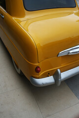 The left rear side of an old yellow taxi.