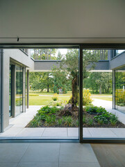 Open glass door of a modern home leading to a beautifully landscaped garden with a pathway.