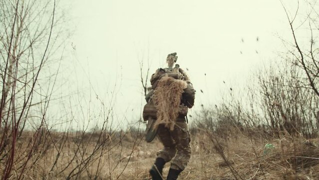 A fully-equipped female sniper navigates the rough terrain, her rifle ready as she heads towards her strategic deployment location. Camera 8K RAW. 