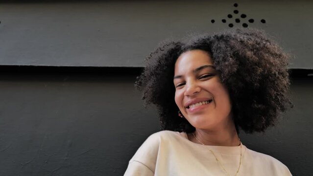 Young woman with curly hair on the black background looking at camera