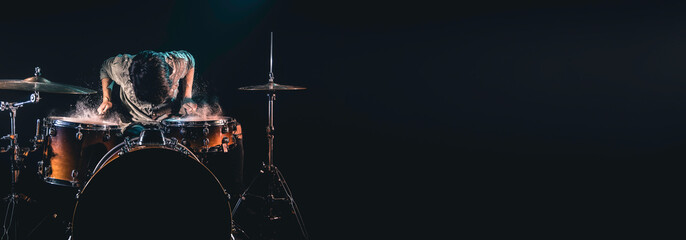 Fototapeta na wymiar Professional drummer playing on drum set on stage on the black background.