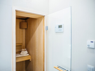 Fototapeta na wymiar Compact modern sauna room with a wooden finish and digital control panel.