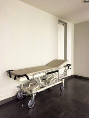 Vertical image of an empty hospital transport bed on the clinic hospital floor with healthcare equipment in the background