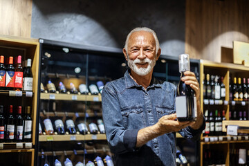 Portrait of a handsome mature man buying wine at a grocery store.