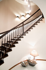 Modern home interior with elegant spiral stairs made of brown woodwork, walls illumination