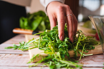 A close up of girl's or woman's hands peeling and cutting vegetables with knife making salad	

