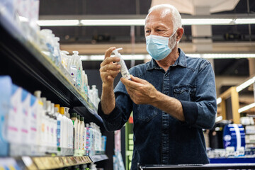 Man wearing protective mask holding grooming product in supermarket. Concept, diseases, viruses,...