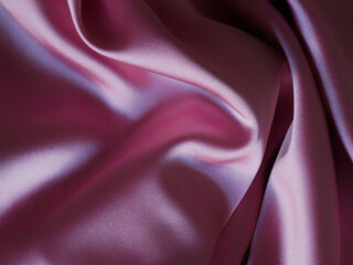 Folds of crumpled pink silk fabric. Close-up photo, background texture