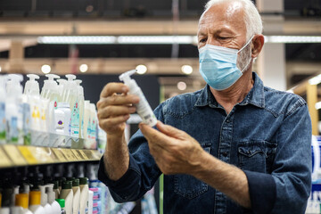 Man wearing protective mask holding grooming product in supermarket. Concept, diseases, viruses,...